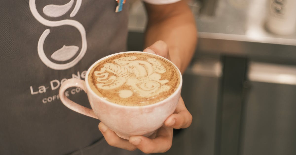 Chai powder being stirred into steamed milk in a glass mug with organic spices