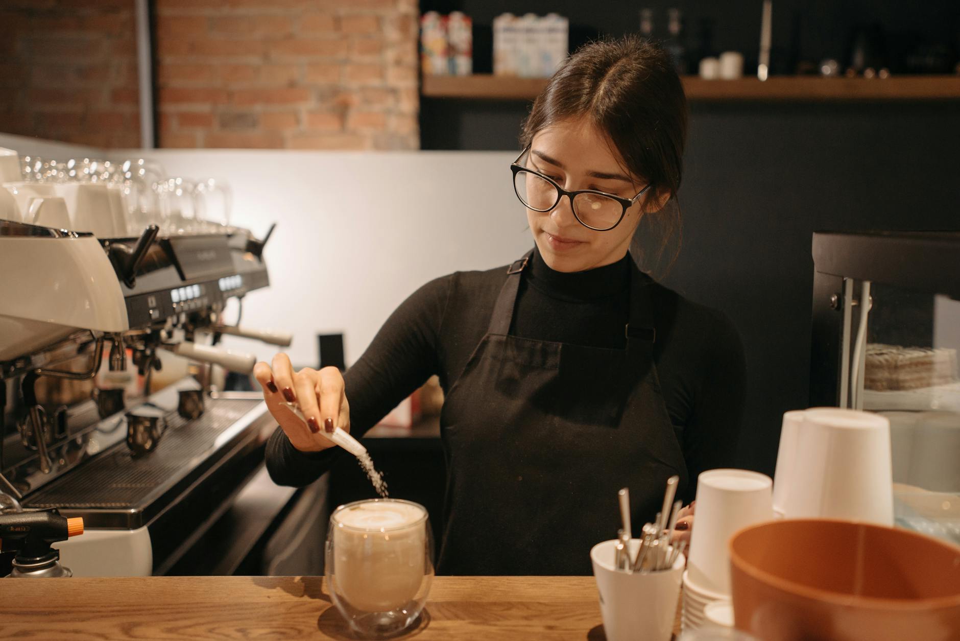 Barista pouring steamed milk into a chai latte at a cafe counter