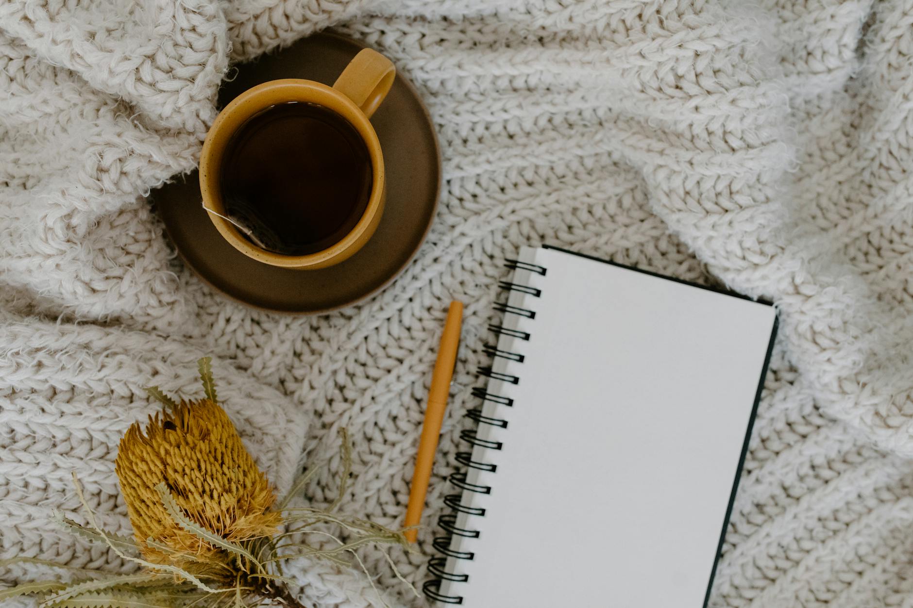 Cozy cup of tea with a notebook on a soft blanket, warm and comforting