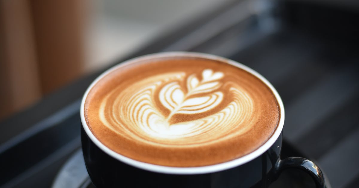 Coffee cup and chai latte side by side on a wooden table