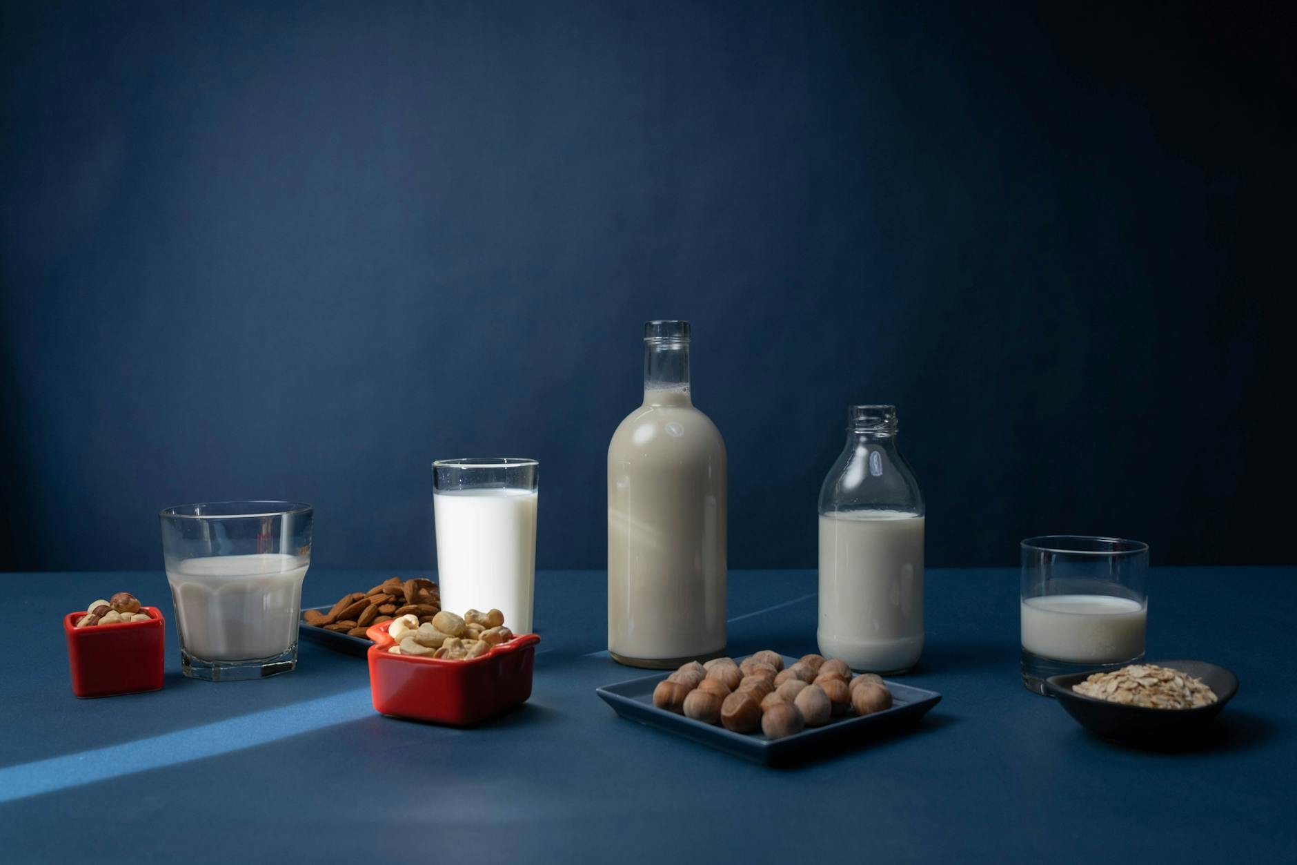Different milk options — oat, almond, whole — in measuring cups