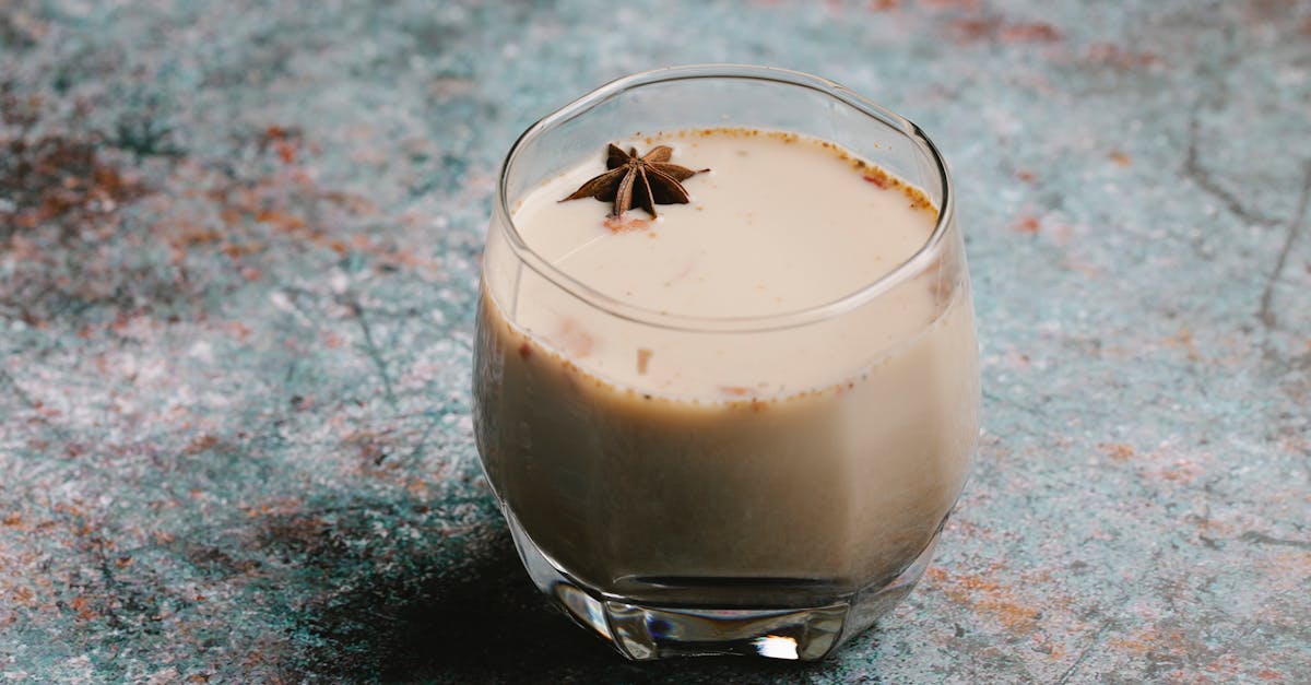Light and creamy chai latte in a clear glass showing layers of steamed milk and chai