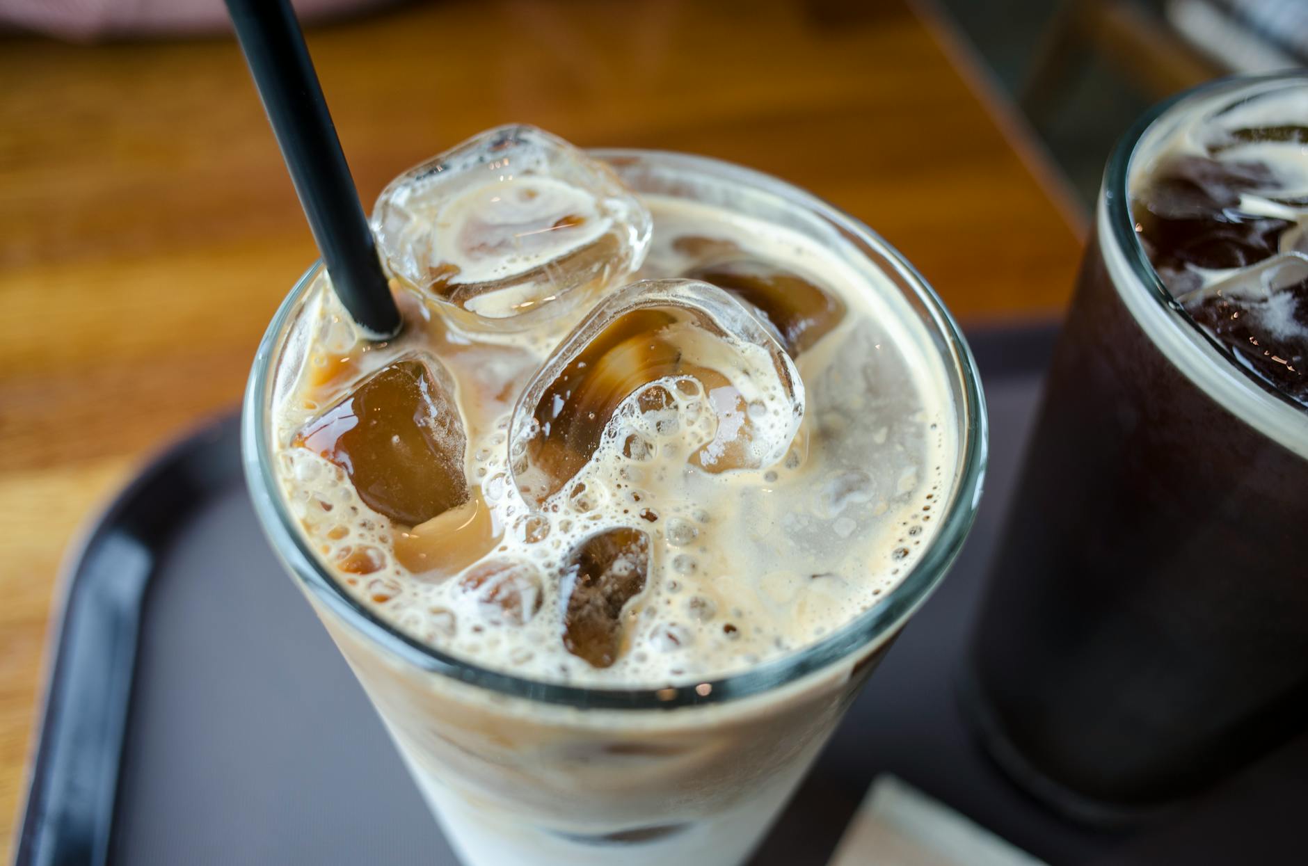 Close-up of iced milk tea with ice cubes and a straw in a tall glass