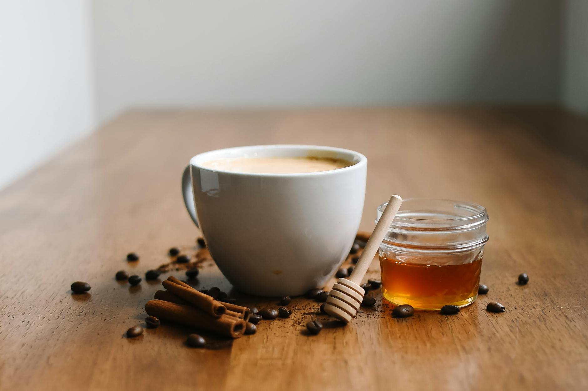Cup of masala chai with honey and cinnamon sticks on a wooden table